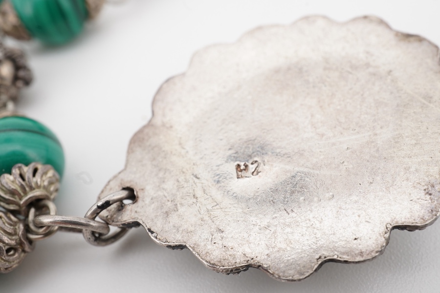 An Arts & Crafts silver and malachite necklace, early 20th century composite, the front composed of malachite beads in silver wire work mounts, suspending a green hardstone pendant in a floral silver border, necklace len